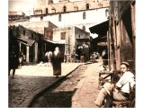 A view of the paved main street of Nazareth, with its wide central gutter to carry off rainwater. We see the Greek Uniate Church, marking the reputed location of the synagogue in which Jesus was taught. An early photograph.